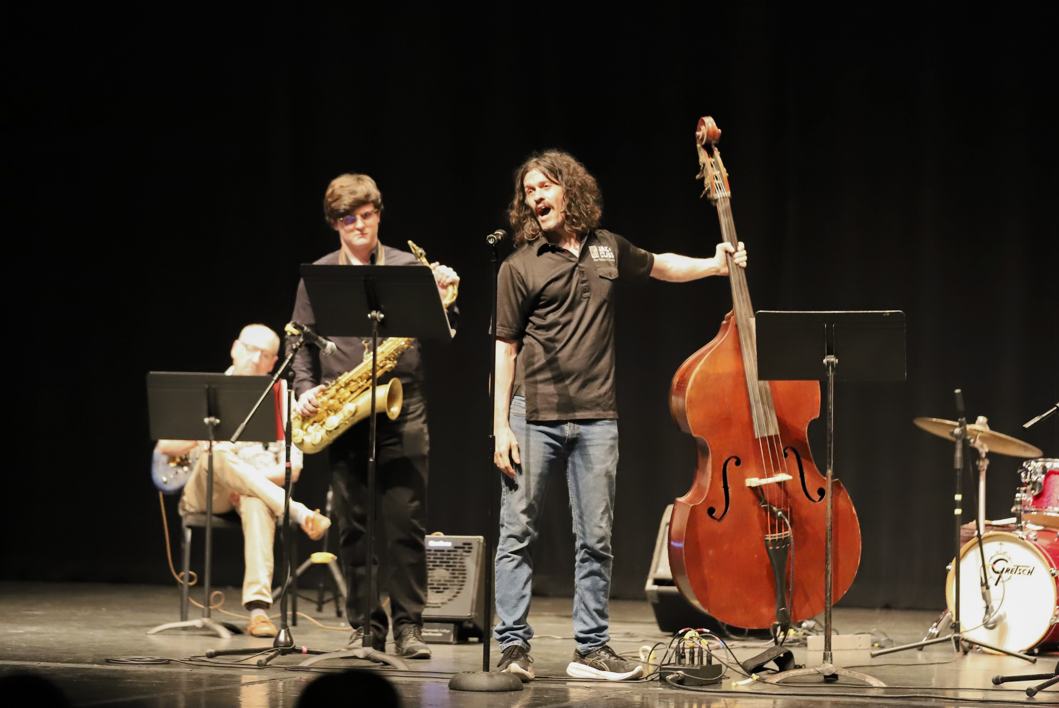 Photo of a string bassist and a saxophone player introducing their spotlight number with the PCC Jazz Band.