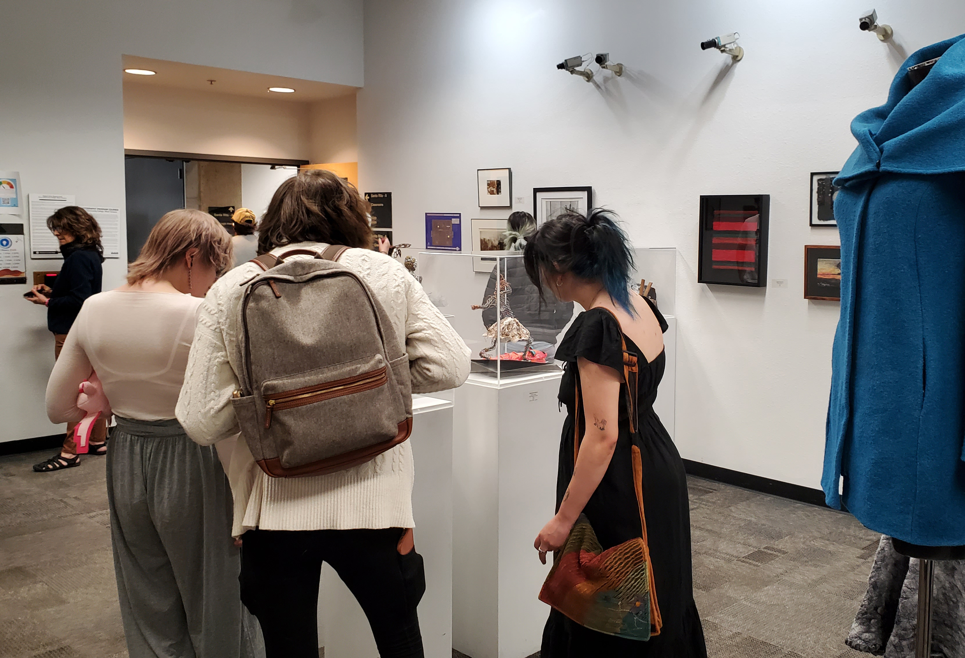 Photo of people looking at artwork at a student art exhibit reception in the Visual Arts Gallery.